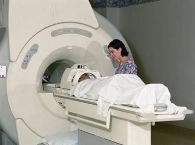 Patient lying in MRI, nurse standing on side